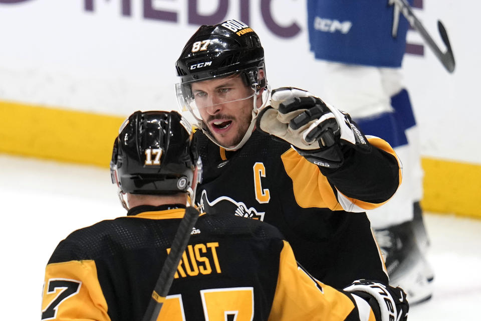 Pittsburgh Penguins' Sidney Crosby (87) celebrates with Bryan Rust after scoring his 40th goal of the season during the first period of an NHL hockey game against the Tampa Bay Lightning in Pittsburgh, Saturday, April 6, 2024. (AP Photo/Gene J. Puskar)