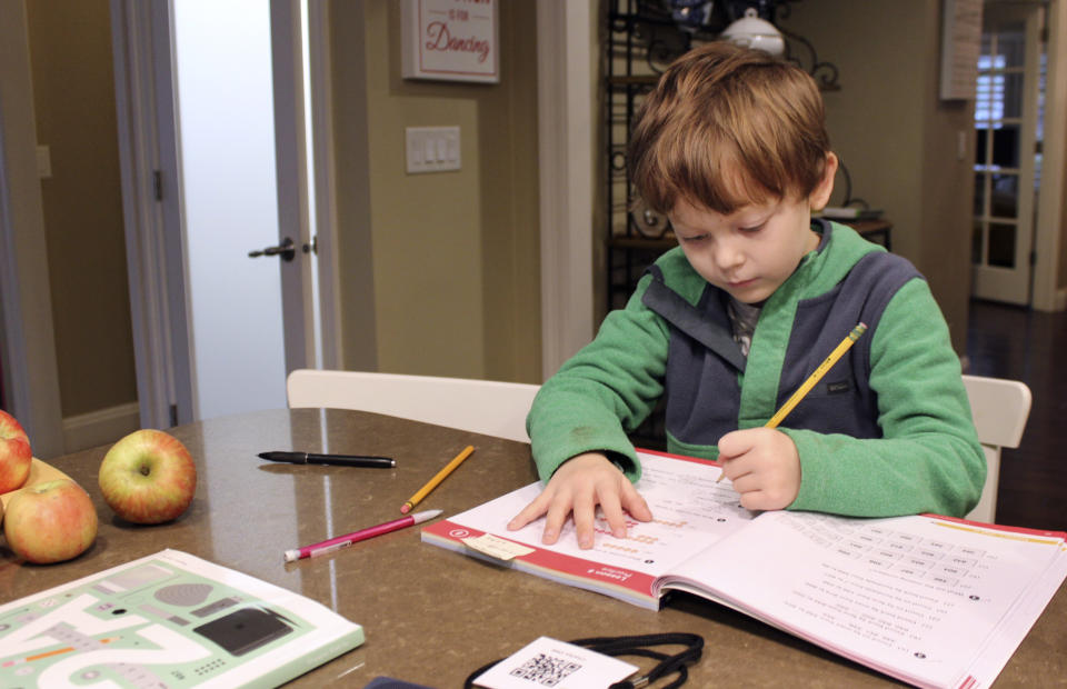 Charlie Dale works on problems in his math notebook at the kitchen counter in his family home in Lake Oswego, Ore., Oct. 30, 2020. Charlie's school has been closed to in-person learning since March. In Oregon, one of only a handful of states that has required a partial or statewide closure of schools in the midst of the COVID-19 pandemic, parents in favor of their children returning to in-person learning have voiced their concerns and grievances using social media, petitions, letters to state officials, emotional testimonies at virtual school board meetings and on the steps of the state's Capitol. (AP Photo/Sara Cline)