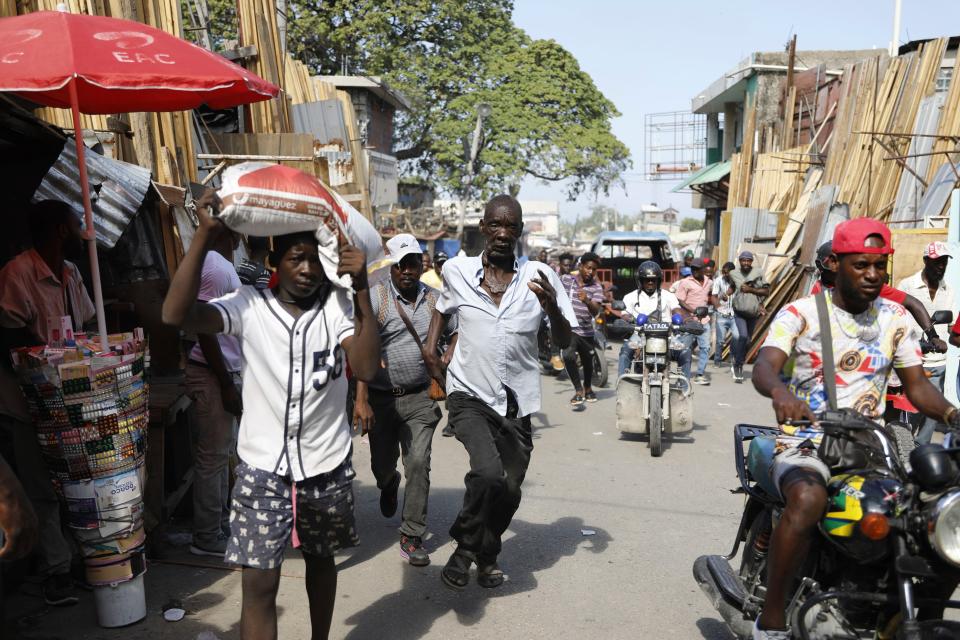 FILE - Pedestrians run for cover after hearing gunshots in Port-au-Prince, Haiti, Thursday, March 7, 2024. Unrelenting gang attacks in Haiti have paralyzed the country and left it with dwindling supplies of basic goods. Worsening the situation is this week's closure of Port-au-Prince's main seaport. The move left stranded scores of containers filled with critical items like food and medical supplies in a country where U.N. officials say half the population does not have enough to eat and 1.4 million are starving. (AP Photo/Odelyn Joseph, FILE)