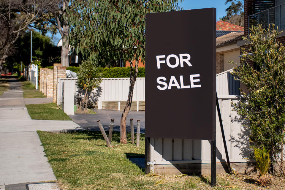 'For sale' sign on black board near a residential property.