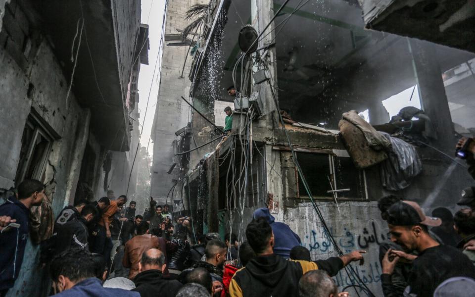 Palestinians look on at the destruction following an Israeli air strike on a house