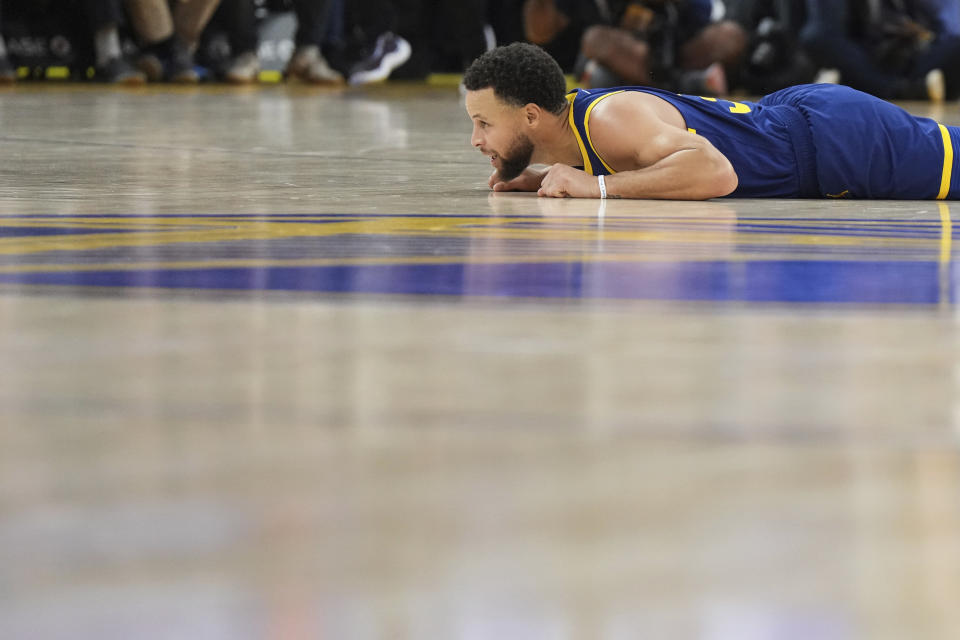 Golden State Warriors guard Stephen Curry lies on the court after being fouled during the first half of the team's NBA basketball game against the Miami Heat on Thursday, Dec. 28, 2023, in San Francisco. (AP Photo/Loren Elliott)