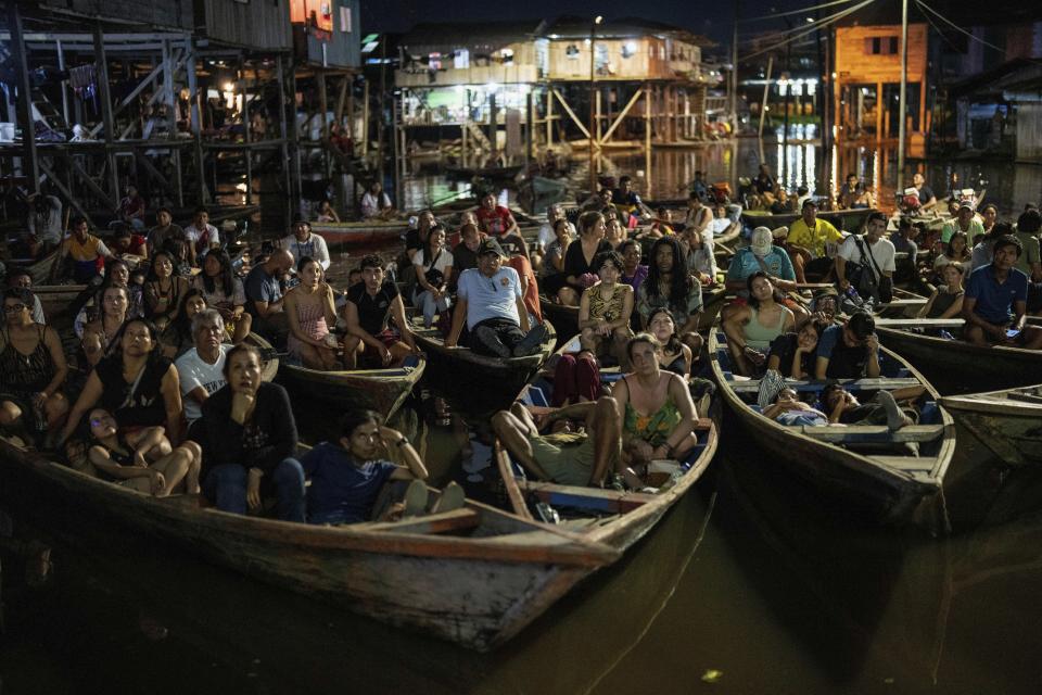Los espectadores se sientan en botes para ver una película proyectada en una pantalla instalada sobre una estructura de madera durante el Festival de Cine Flotante Muyuna, que celebra los bosques tropicales, en el barrio Belén de Iquitos, Perú, el sábado 25 de mayo de 2024. (Foto AP/Rodrigo abd)
