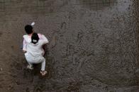 A man crosses a mud-covered trail carrying his wife on his back at a flooded Han River park in Seoul