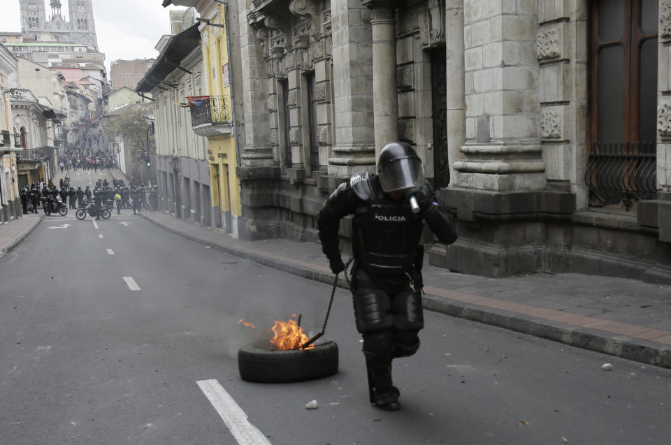 A police officer removes a burning tire placed by people holding a transportation strike to protest the president in Quito, Ecuador, Thursday, Oct. 3, 2019. Ecuador’s president has declared a state of emergency to confront rowdy street protests and a nationwide transport strike over his decision to end government fuel subsidies and relax labor protections. (AP Photo/Dolores Ochoa)