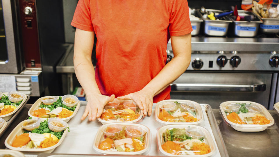 Midsection of female chef packing food on kitchen counter in restaurant