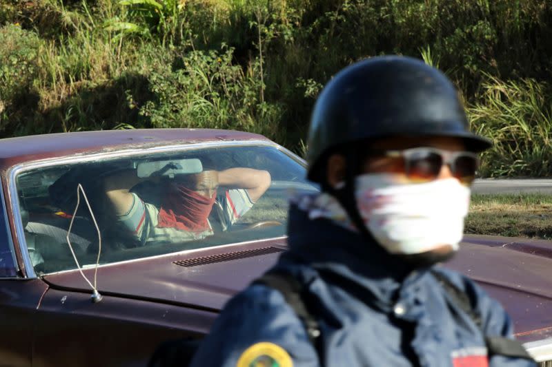 A man wraps a piece of cloth around his face at a checkpoint after the start of quarantine in response to the spreading coronavirus disease (COVID-19) in Caracas