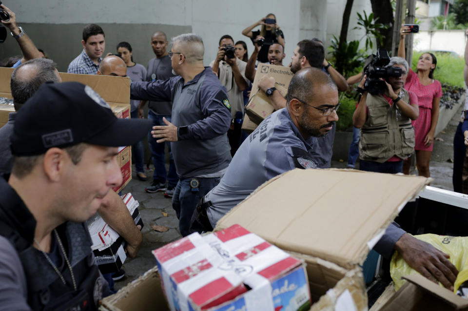 Policemen unload items at Civil Police headquarters in Rio de Janeiro, Brazil, Tuesday, March 12, 2019, that were confiscated from the home of the suspects in the killing of councilwoman Marielle Franco. The brazen assassination of the councilwoman and her driver on March 14 last year led to massive protests and widespread anger in Latin America's largest nation. Two suspects have been arrested. (AP Photo/Silvia Izquierdo)