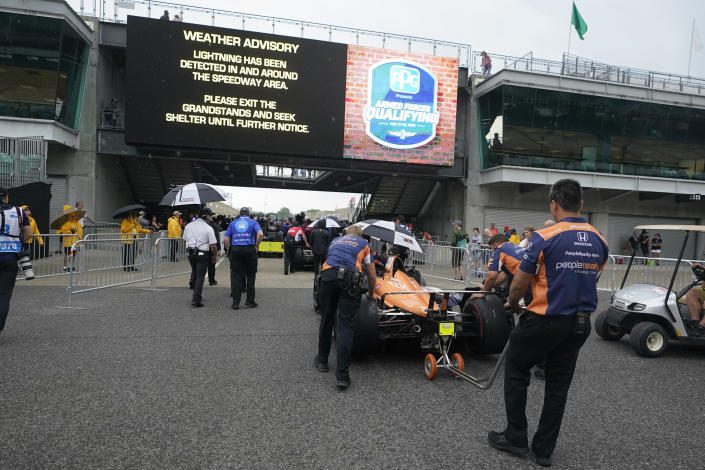 The crew for Christian Lundgaard, of Denmark, push his car back to Gasoline Alley during a weather delay during qualifications for the Indianapolis 500 auto race at Indianapolis Motor Speedway, Saturday, May 21, 2022, in Indianapolis. (AP Photo/Darron Cummings)