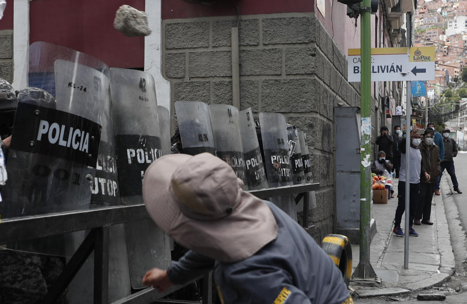 Un hombre lanza una piedra a la policía frente al palacio de gobierno durante una protesta en apoyo a los trabajadores de la salud en medio de la pandemia de COVID-19 en La Paz, Bolivia, el lunes 22 de febrero de 2021. Los trabajadores de la salud han convocado una huelga general para protestar contra una nueva ley sanitaria de emergencia que, entre otras cosas, permite la contratación de médicos extranjeros. (AP Foto/Juan Karita)