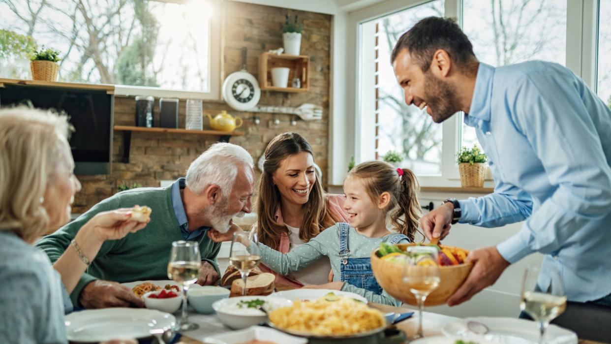 Happy multi-generation family gathering around dining table and having fun during a lunch.