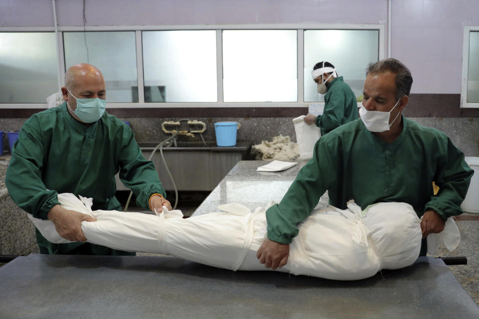 Cemetery workers the prepare the body of a person who died from COVID-19 for a funeral, at the Behesht-e-Zahra cemetery just outside Tehran, Iran, Wednesday, April 21, 2021. After facing criticism for downplaying the virus last year, authorities have put partial lockdowns and other measures in place to try and slow the coronavirus’ spread, as Iran faces what looks like its worst wave of the coronavirus pandemic yet. (AP Photo/Ebrahim Noroozi)