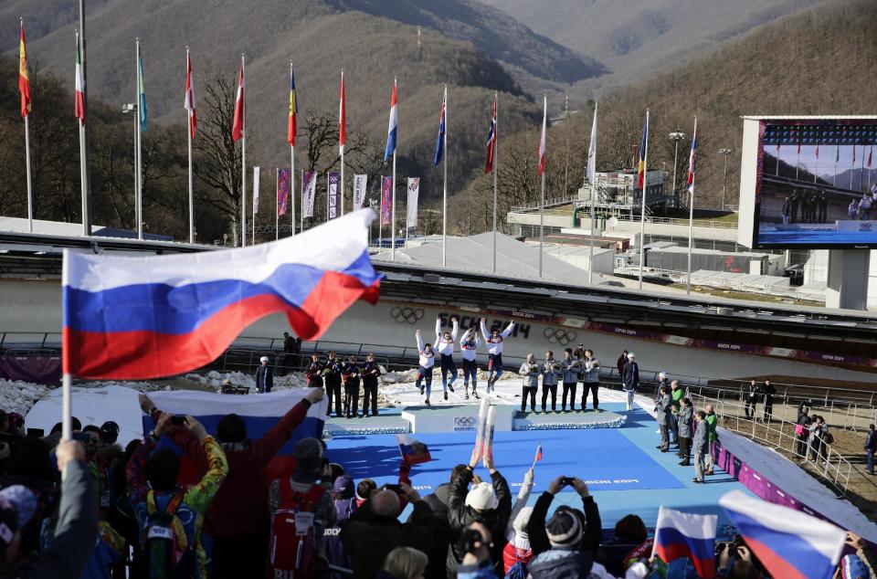 The team from Russia RUS-1, with Alexander Zubkov, Alexey Negodaylo, Dmitry Trunenkov, and Alexey Voevoda, jump onto the medal stand after they won the gold medal during the men's four-man bobsled competition final at the 2014 Winter Olympics, Sunday, Feb. 23, 2014, in Krasnaya Polyana, Russia. (AP Photo/Jae C. Hong)