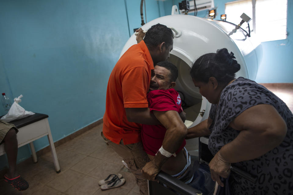 En esta fotografía del 9 de febrero de 2018 el buzo Misael Banegas, paralizado por el síndrome de descompresión, es levantado por un terapeuta físico para llevarlo a una cámara hiperbárica en el hospital de Puerto Lempira, Honduras. (AP Foto/Rodrigo Abd)