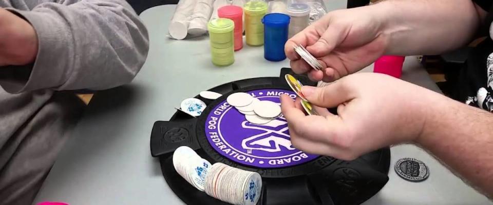 Closeup of pogs match with hands holding pogs