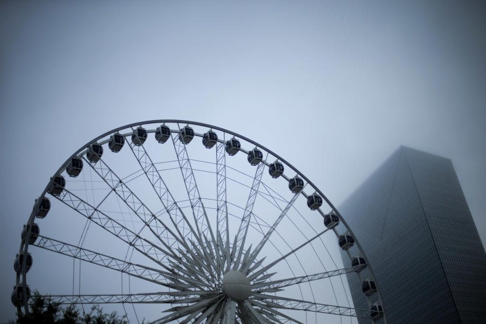 Early morning fog blankets downtown as one of Atlanta's newest attractions, a 200 foot tall Ferris wheel, is set to open to the public today, Tuesday, July 16, 2013, in Atlanta. SkyView Atlanta is scheduled to open at noon Tuesday and offer riders a bird's eye view of the city during its 15-minute trips near Centennial Olympic Park. According to the attraction's website, rides for adults will cost $14.45, $13 for seniors and members of the military, and $9.10 for children. Each gondola is required to have an adult riding in it along with the children. The wheel was previously in Paris and in Pensacola, Fla. (AP Photo/David Goldman)
