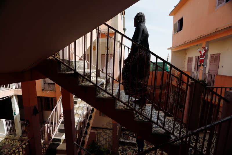 Woman who said she was raped twice, walks up the stairs at La Maison Rose in Dakar