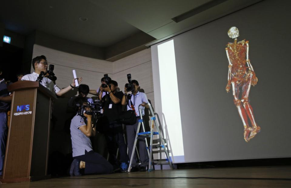 Seo Joong-seok (L), director general of South Korea's National Forensic Service (NFS), gives a briefing on the cause of death of businessman Yoo Byung-un, as a 3D scanned image of Yoo's body is projected on a screen at the agency office in Seoul July 25, 2014. The agency said on Friday it was impossible to determine the cause of death of Yoo, who is linked to a ferry that sank and killed 304 people in April, deepening the mystery surrounding the final days of Korea's most wanted man. An autopsy and DNA tests on his badly decomposed body revealed no evidence that he was poisoned, and there was also no indication of external trauma, forensic agency chief Seo told a news conference. REUTERS/Kim Hong-Ji (SOUTH KOREA - Tags: DISASTER CRIME LAW TPX IMAGES OF THE DAY)