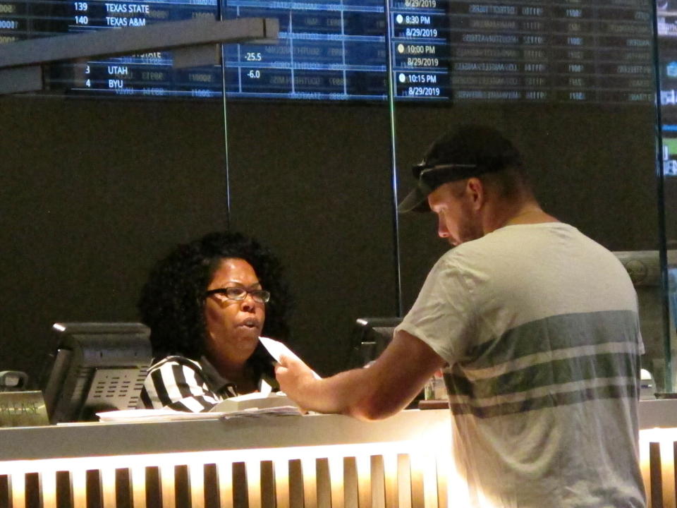 In this June 27, 2019 photo, a gambler places a bet at the new sportsbook at Bally's casino in Atlantic City, N.J. New Jersey surpassed Nevada in terms of sports betting volume in May, taking the national lead for the first time. (AP Photo/Wayne Parry)