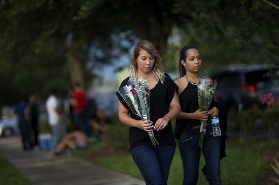 <p>Mourners carry flowers into the visitation for Pulse nightclub shooting victim Javier Jorge-Reyes, in Orlando. (Photo: David Goldman/AP) </p>