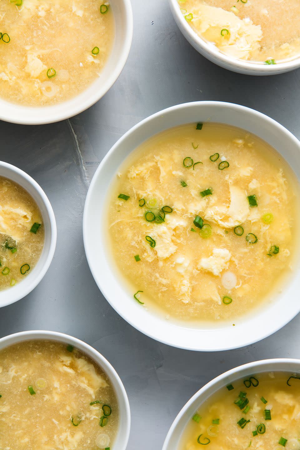 egg drop soup garnished with scallions in white bowls