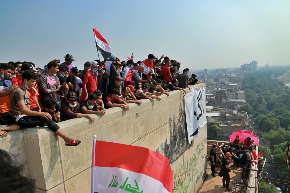 In this Oct. 31, 2019, photo, Iraqi anti-government protesters stand on a building near Tahrir Square, Baghdad, Iraq. An abandoned building in central Baghdad has emerged as the epicenter of anti-government protests in Iraq, with hundreds holed up inside. The Saddam Hussein-era building known as the “Turkish Restaurant” overlooks Tahrir Square, the Tigris River and the Green Zone, and protesters who took it over on Oct. 25 have sworn not to leave it. (AP Photo/Hadi Mizban)