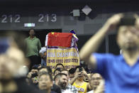 A fan drapes a Chinese national flag over an NBA banner during a preseason NBA basketball game between the Brooklyn Nets and Los Angeles Lakers at the Mercedes Benz Arena in Shanghai, China, Thursday, Oct. 10, 2019. In response to the NBA defending Daryl Morey's freedom of speech, Chinese officials took it away from the Los Angeles Lakers and Brooklyn Nets. All of the usual media sessions surrounding the Lakers-Nets preseason game in Shanghai on Thursday — including a scheduled news conference from NBA Commissioner Adam Silver and postgame news conferences with the teams — were canceled. It was the latest salvo in the rift between the league and China stemming from a since-deleted tweet posted last week by Morey, the general manager of the Houston Rockets. (AP Photo)