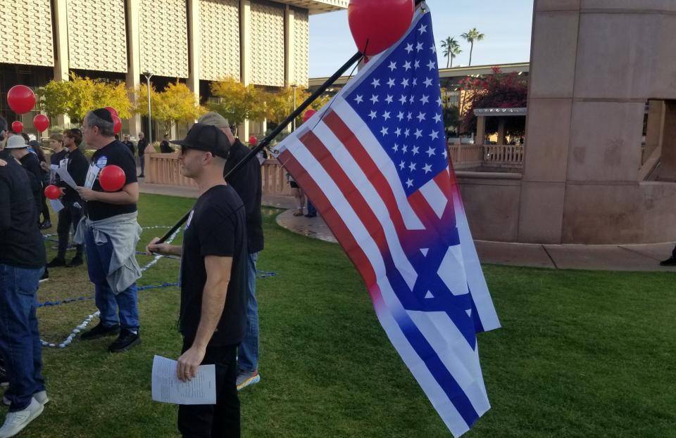 Sam Sternberg holds a flag while listening to speakers during a rally Sunday, Dec. 3, 2023 at Hayden Lawn at Arizona State University in Tempe. The crowd stood in support of releasing Hamas hostages.