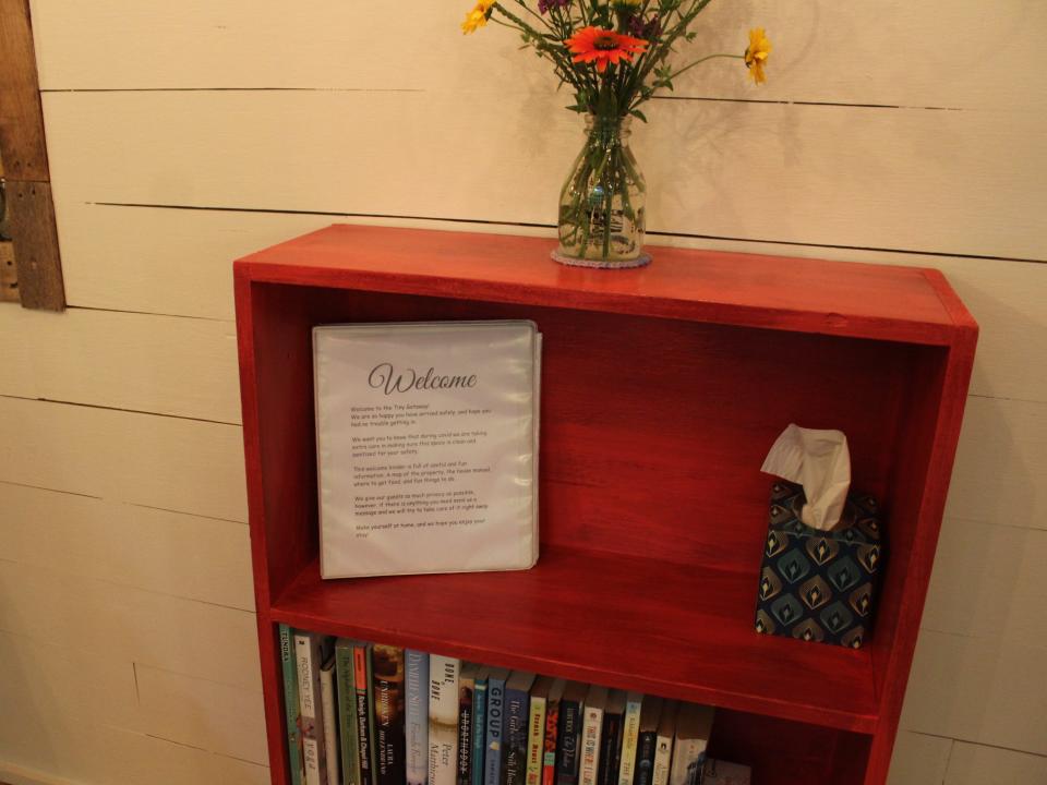 a book shelf inside the tiny house with the welcome book