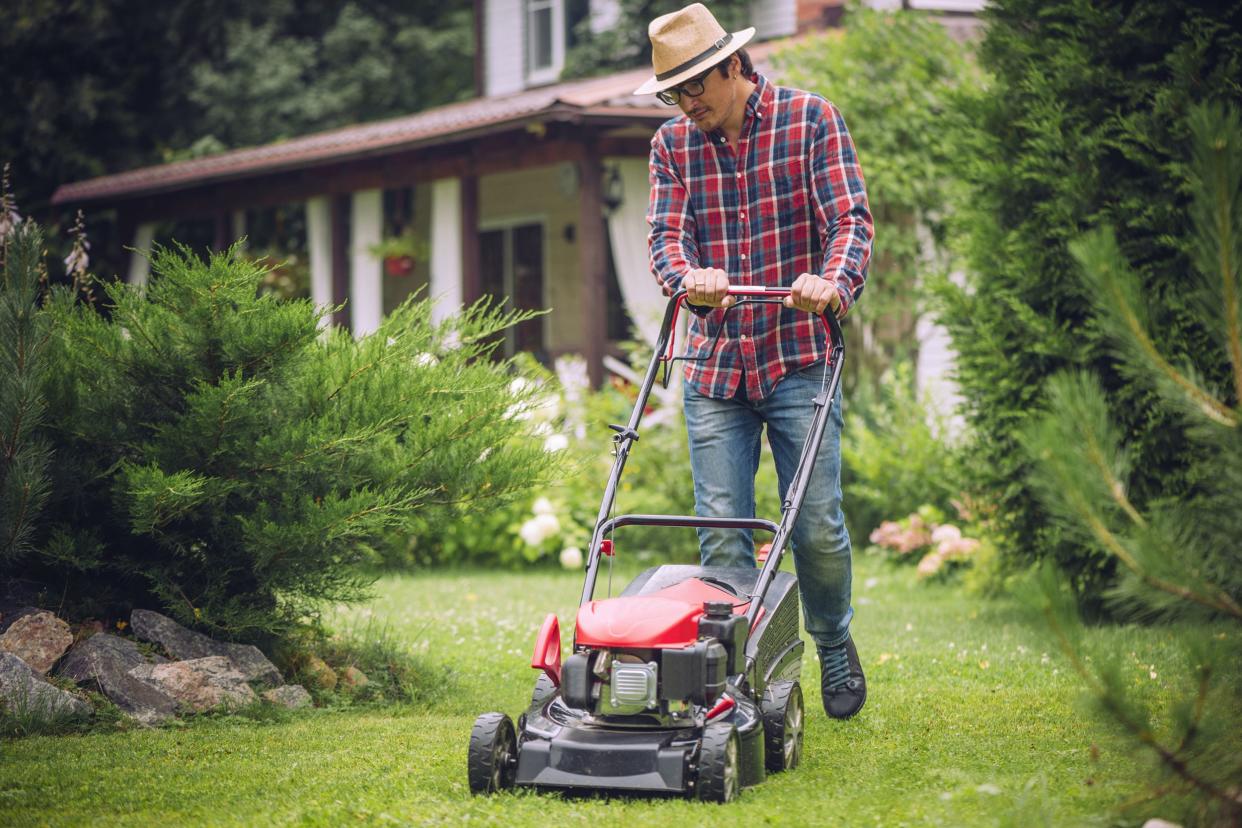 man using a lawn mower in his back yard