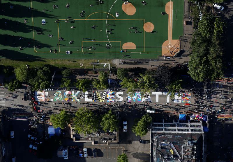 Artists decorate a Black Lives Matter mural on the street near the Seattle Police Department's East Precinct in Seattle