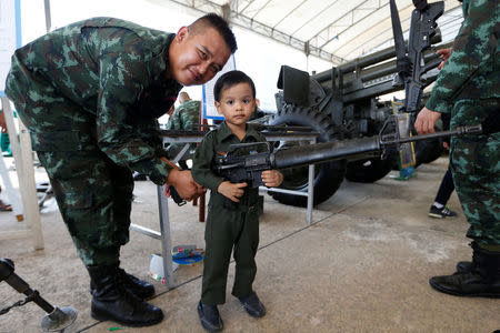 A boy and a Thai army soldier pose with a weapon during Children's Day celebration at a military facility in Bangkok, Thailand January 14, 2017. REUTERS/Jorge Silva