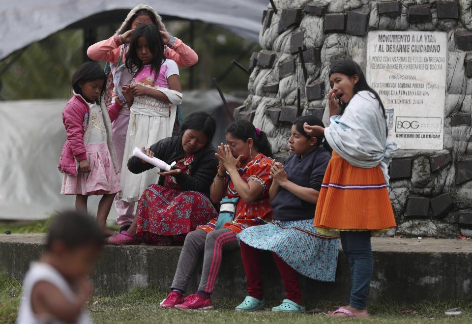 Miembros de la tribu Embera-Katio comparten una botella de crema corporal en un parque donde establecieron un refugio tras ser desalojados de sus horas por no pagar la renta debido a la pandemia del nuevo coronavirus en Bogotá, Colombia, el viernes 19 de junio de 2020. (AP Foto/Fernando Vergara)