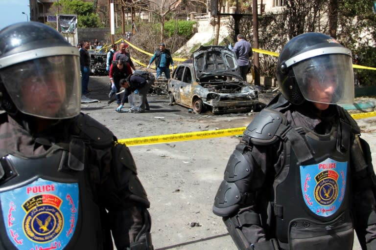 Egyptian forensics check a destroyed vehicle at the site of a bomb attack in the northern port city of Alexandria, which hit a convoy of the city's security chief, on March 24, 2018