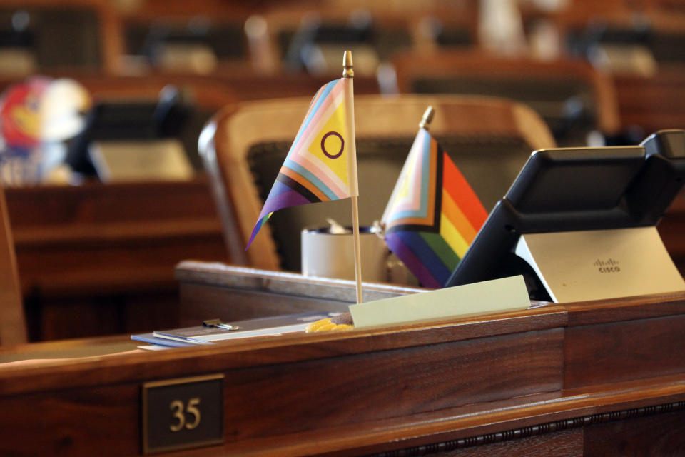 Small flags promoting transgender rights sit on the Kansas House chamber desks of, state Rep. Jarrod Ousley, D-Merriam, left, and Allison Hougland, D-Olathe, right, following the House's session, Wednesday, March 27, 2024, at the Statehouse in Topeka, Kan. Both lawmakers oppose a proposed ban on gender-affirming care for transgender minors. (AP Photo/John Hanna)