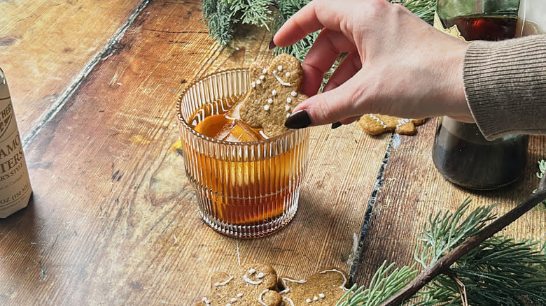 hand adding gingerbread cookie to drink