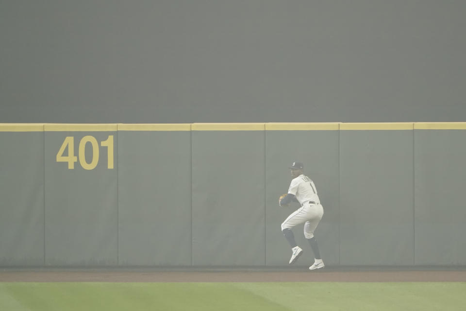 Seattle Mariners center fielder Kyle Lewis prepares to throw the ball back to the infield after making a catch as the air is filled with wildfire smoke during the first baseball game of a doubleheader against the Oakland Athletics, Monday, Sept. 14, 2020, in Seattle. (AP Photo/Ted S. Warren)