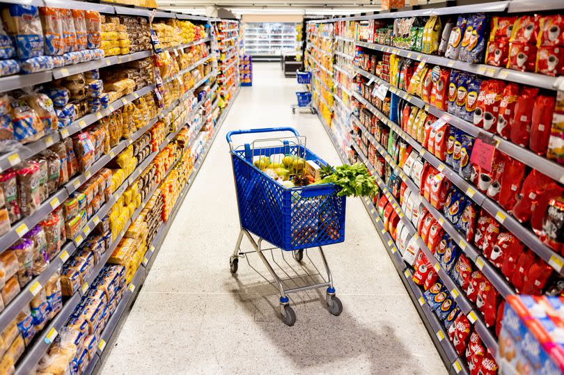 Shopping cart in the middle on an aisle at the supermarket - grocery shopping concepts