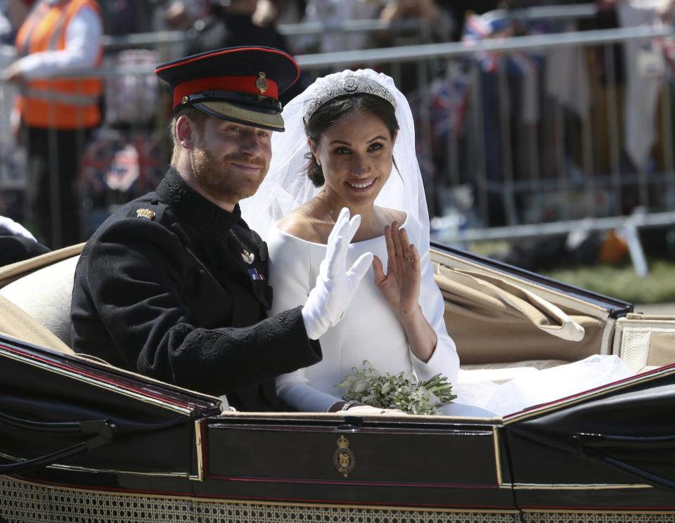 FILE - In this May 19, 2018 file photo, Britain's Prince Harry and Meghan Markle ride in an open-topped carriage after their wedding ceremony at St. George's Chapel in Windsor Castle in Windsor, near London, England. (Aaron Chown/pool photo via AP)