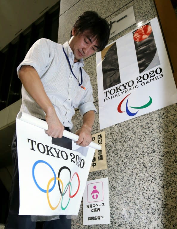 A Tokyo metropolitan government officer removes a poster of the logo of the Tokyo 2020 Olympic Games at the Tokyo city hall on September 1, 2015