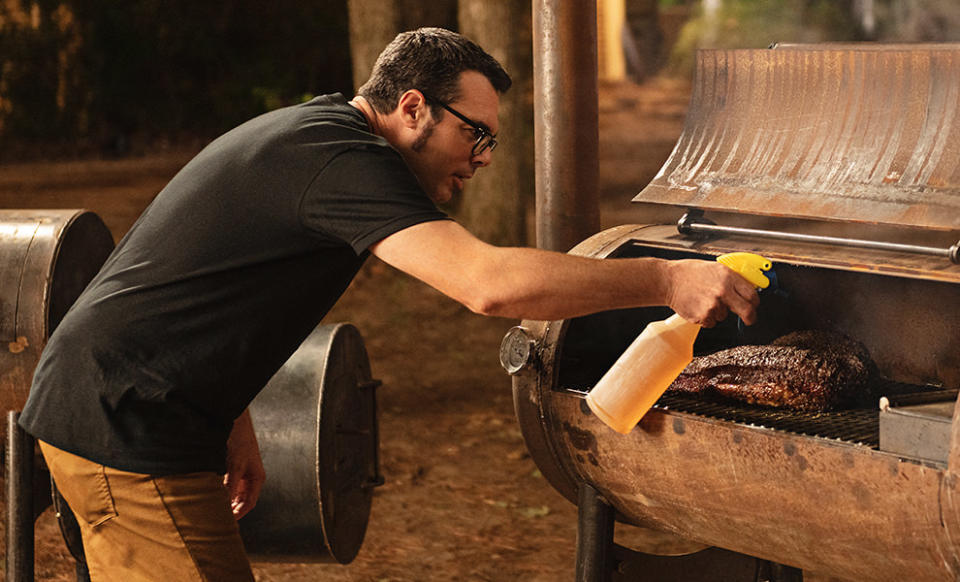 aaron franklin spraying meat in a bbq smoker