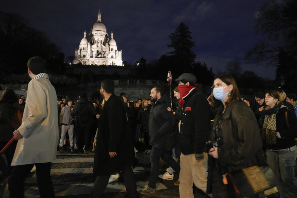 Protesters pass by the Montmartre Sacré-Coeur Basilica during a protest in Paris, Wednesday, March 22, 2023. Macron said Wednesday that the pension bill he pushed through without a vote in parliament needs to be implemented by the "end of the year,” sticking to his decision to raise the retirement age from 62 to 64 despite mass protests. (AP Photo/Lewis Joly)