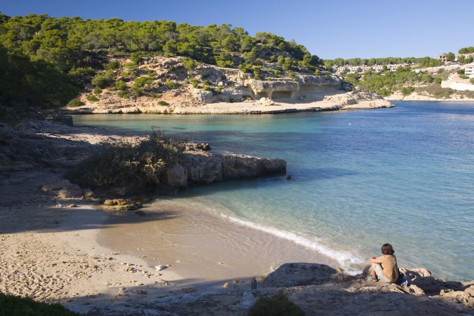 woman on coastal rocks of cala portals vells, near magaluf