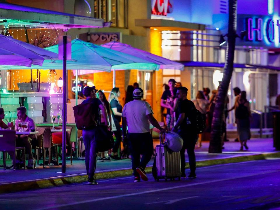 Spring breakers walk down a street at night in Miami.