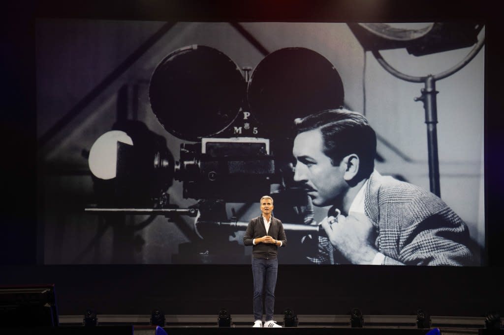 Josh D'Amaro stands in front of a portrait of Walt Disney