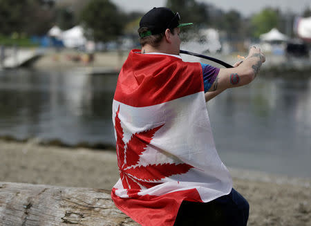 Kevin Lachapelle, 31, of Nanaimo is draped in a pot-leaf flag as he smokes from a pipe at the annual 4/20 marijuana event at Sunset Beach in Vancouver, British Columbia, Canada April 20, 2017. REUTERS/Jason Redmond