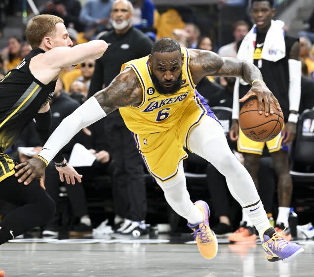 Lakers forward LeBron James leans down and dribbles around Warriors guard Donte DiVincenzo