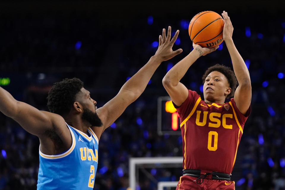 Southern California guard Boogie Ellis, right, shoots as UCLA forward Cody Riley defends during the first half of an NCAA college basketball game Saturday, March 5, 2022, in Los Angeles. (AP Photo/Mark J. Terrill)