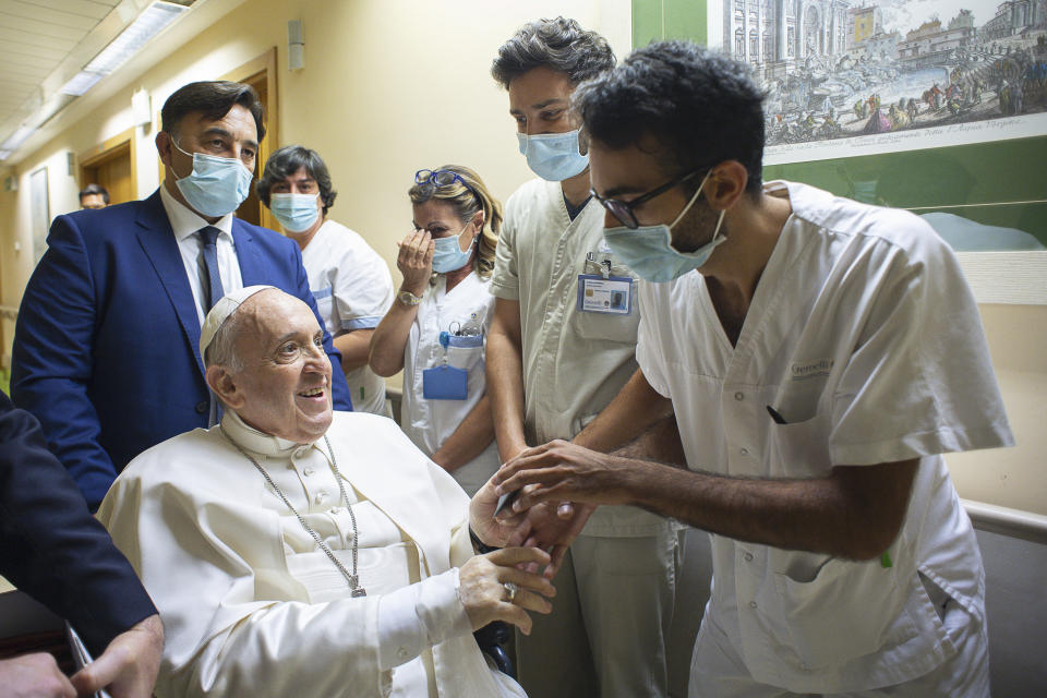 Pope Francis is greeted by hospital staff as he sits in a wheelchair inside the Agostino Gemelli Polyclinic in Rome, Sunday, July 11, 2021, where he was hospitalized for intestine surgery. (Vatican Media via AP)