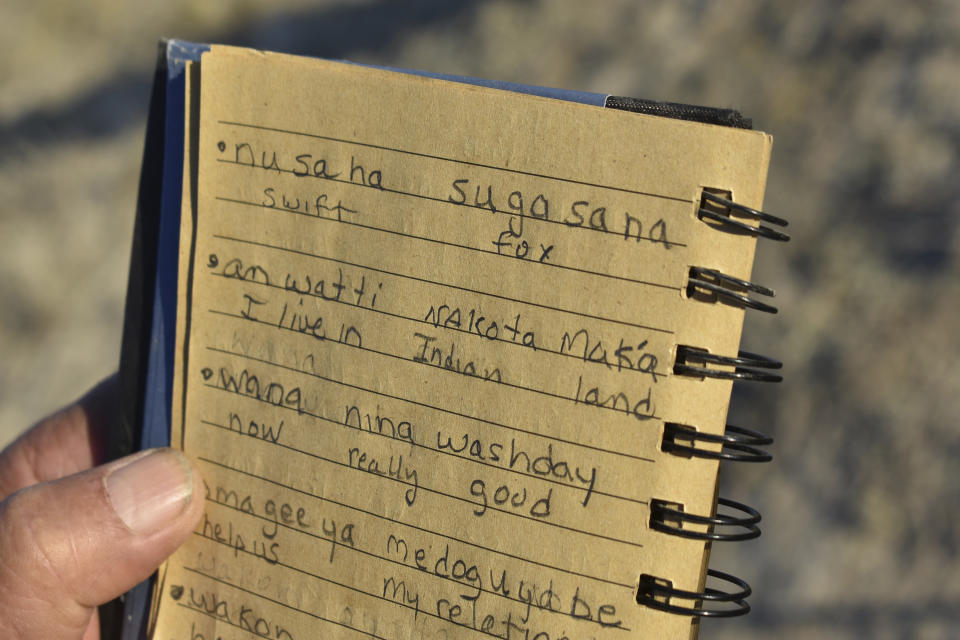 Tribal elder John Allen holds up a notebook with translations of English words into his native Lakota language, including "nusaha sugasana" for the swift fox that is being reintroduced to the Fort Belknap Indian Reservation Wednesday, Sept. 28, 2022, near Fort Belknap Agency, Mont. Native species such as swift foxes and black-footed ferrets disappeared from the Fort Belknap Indian Reservation generations ago, wiped out by poisoning campaigns, disease and farm plows that turned open prairie where nomadic tribes once roamed into cropland and cattle pastures. (AP Photo/Matthew Brown)